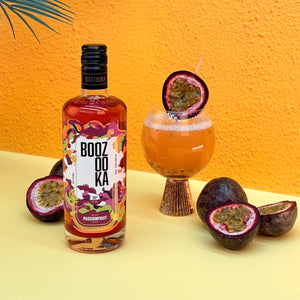 Boozooka passionfruit bottle with a cocktail and passion fruits on an dark yellow background