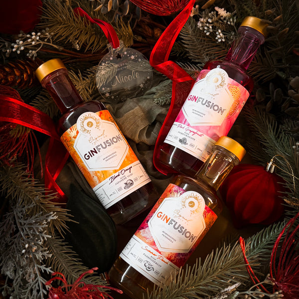 Three bottles of GinFusion on a festive background with Christmas decorations.