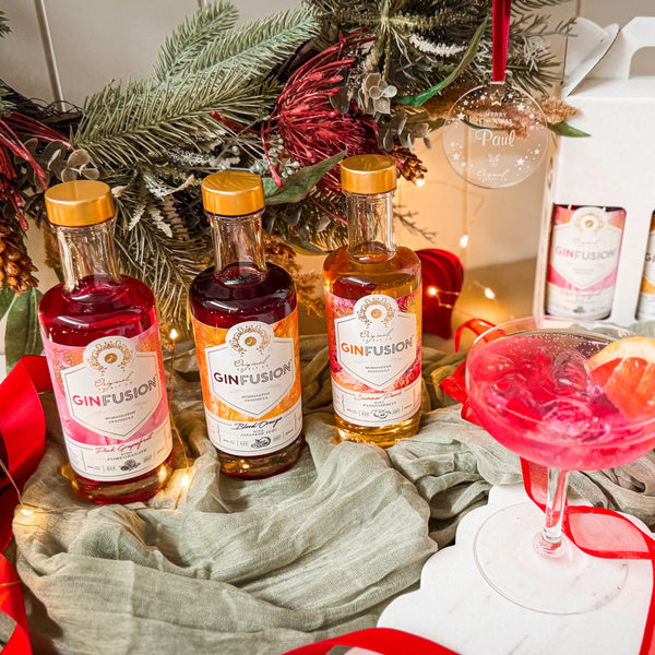 Three bottles of Ginfusion gin with a cocktail glass and Christmas wreath in the background