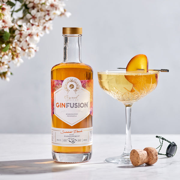 Peach Passionfruit GinFusion cocktail in coupe glass with a peach slice garnish on a pick.