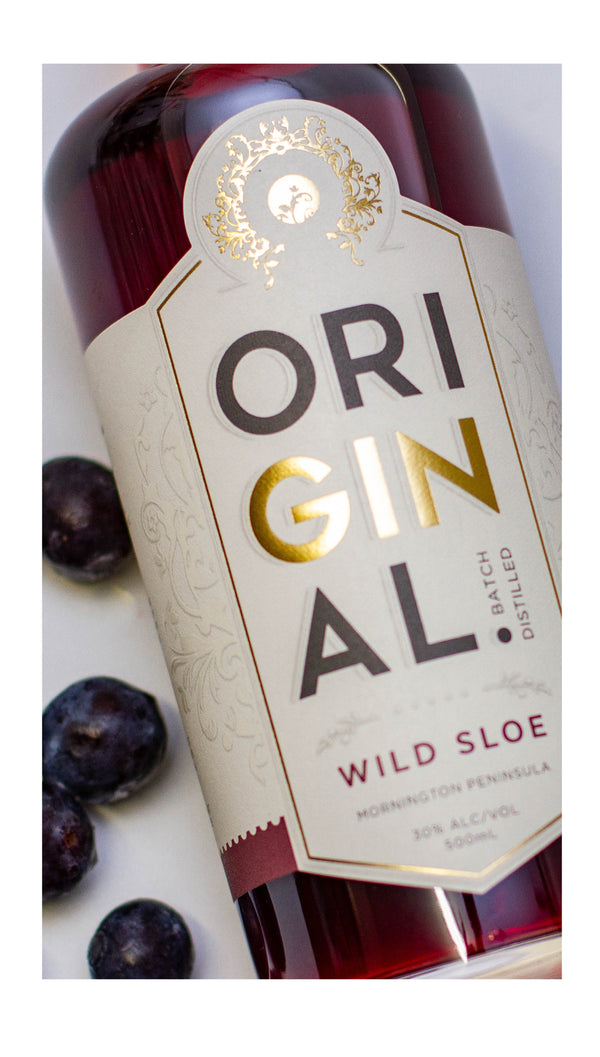 Close up image of the label of a bottle of Original Wild Sloe Gin wth some sloe berries surrounding bottle.