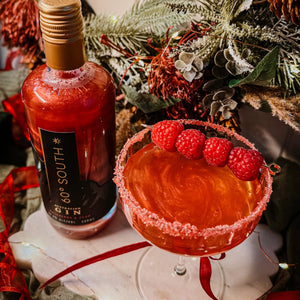 Red Raspberry and Pear 60º Degree South Gin and a cocktail with raspberries on a decorative surface.