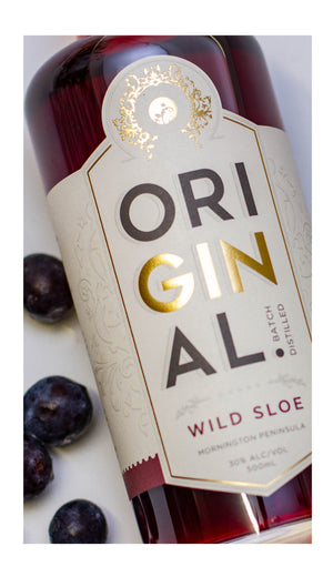 Close up image of the label of a bottle of Original Wild Sloe Gin wth some sloe berries surrounding bottle. 